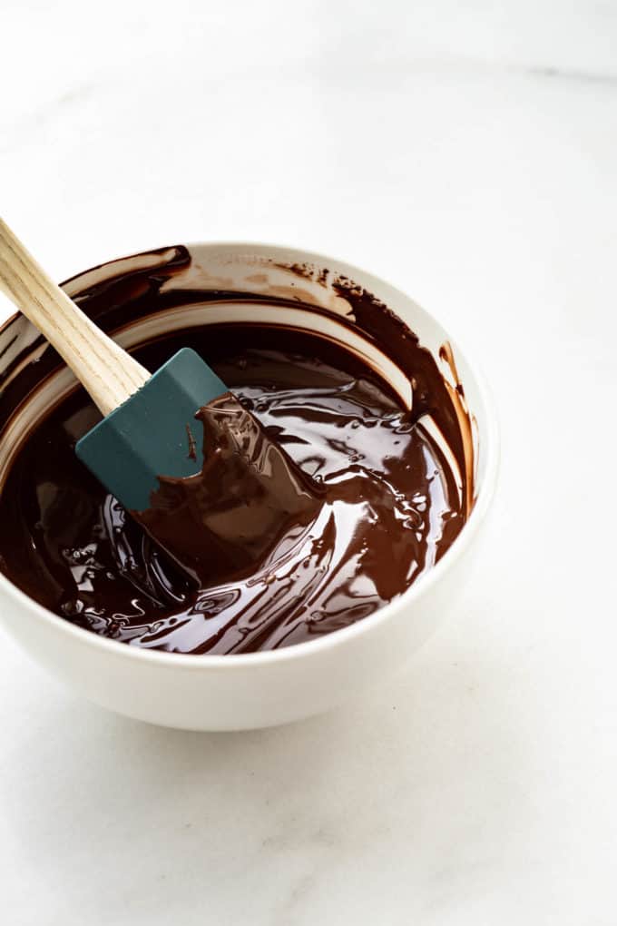 Melted dark chocolate in a white bowl with a spatula
