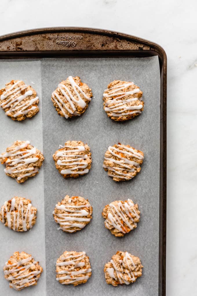glazed carrot cake cookies on a baking sheet with parchment paper