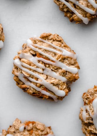 A carrot cake cookie topped with glaze on a marble board