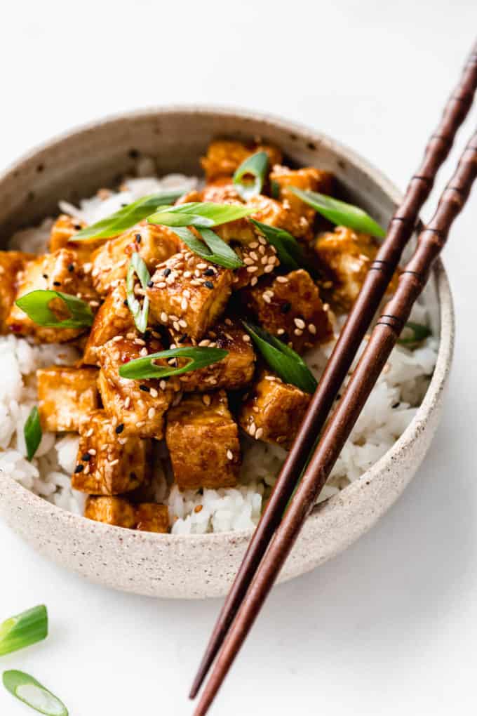 teriyaki tofu in a ceramic bowl with wooden chopsticks