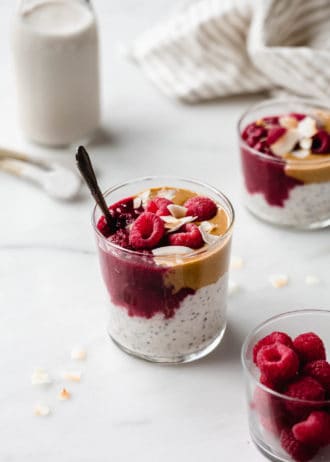 A cup of peanut butter overnight oats with jam and raspberries
