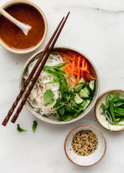 A spring roll noodle bowl with almond butter sauce on the side