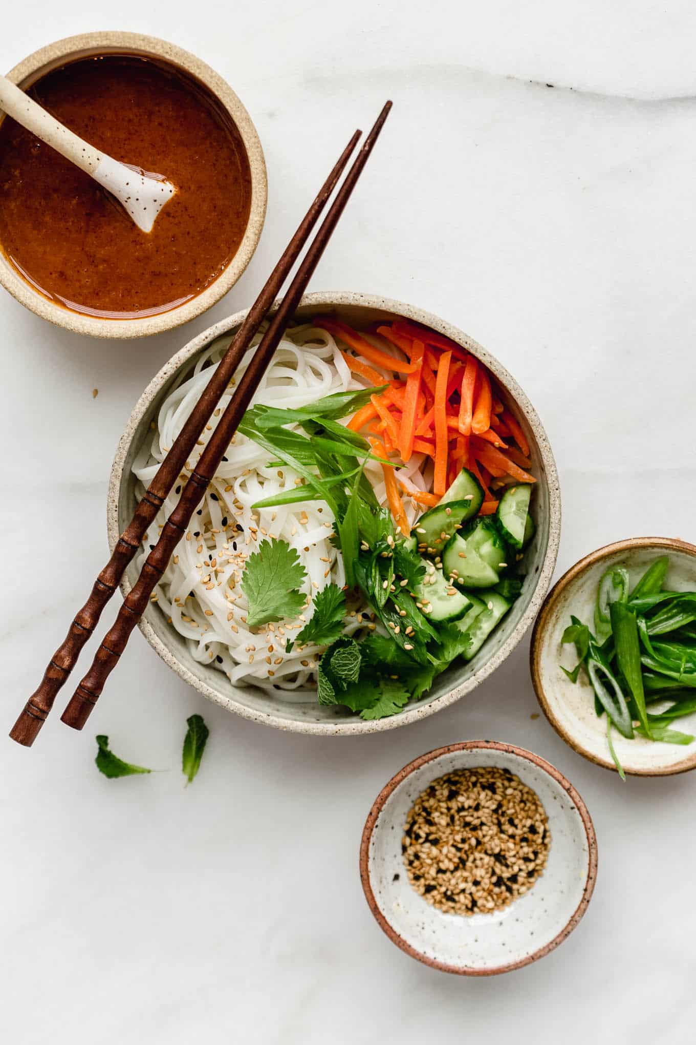 A spring roll noodle bowl with almond butter sauce on the side