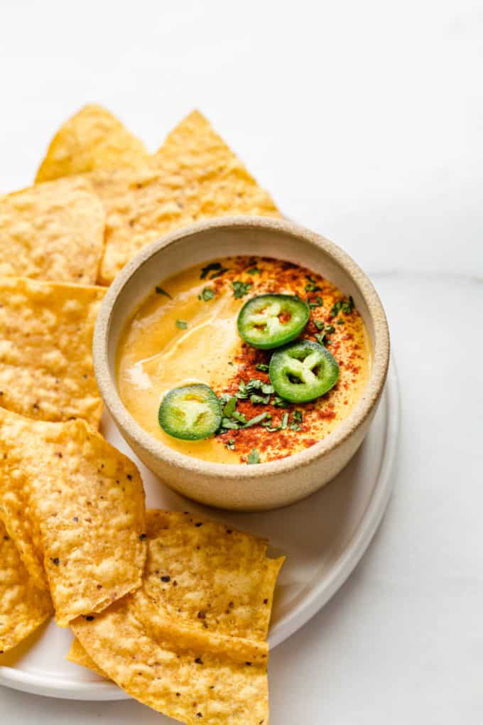 a small bowl of vegan queso with tortilla chips on the side