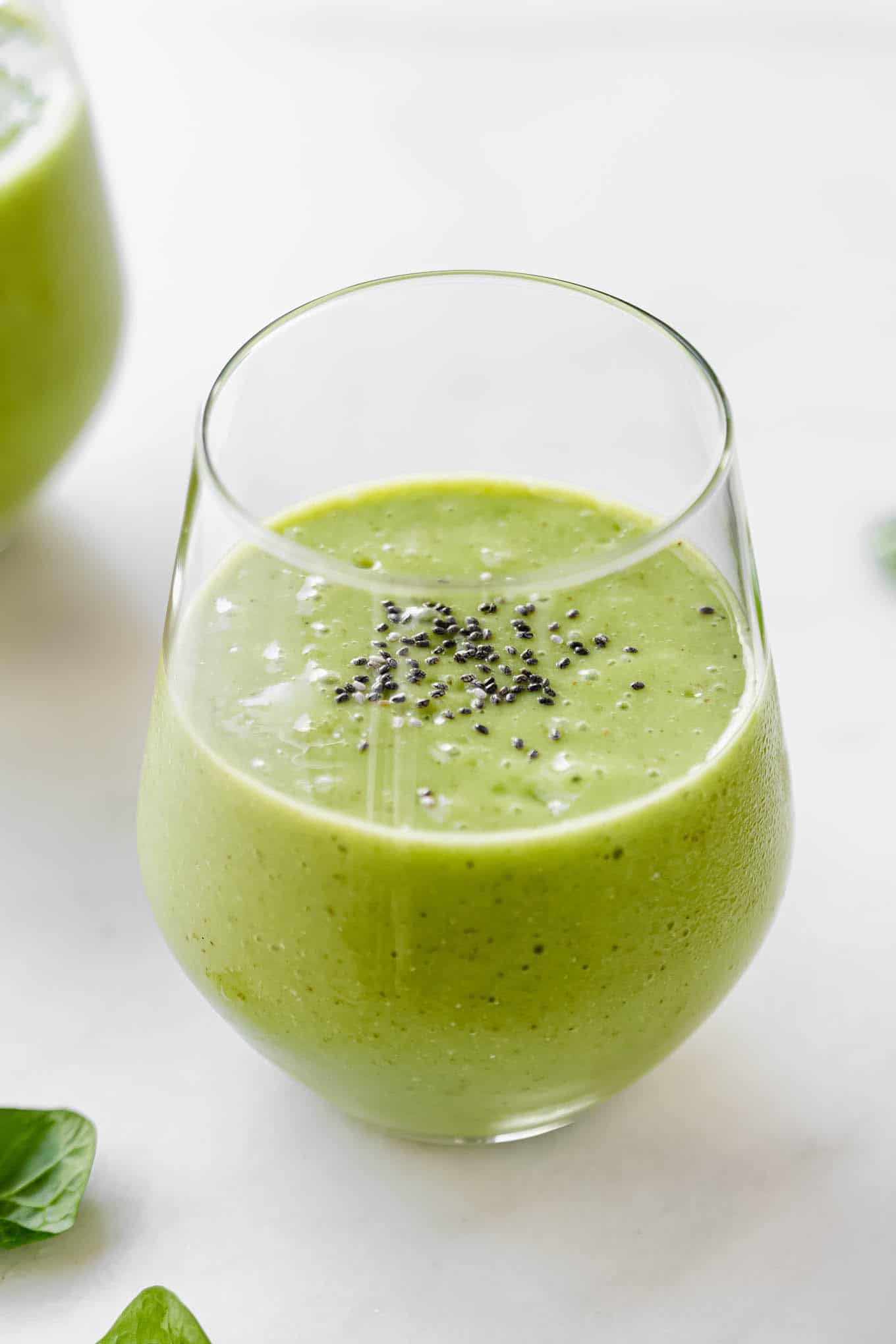 A green smoothie in a glass topped with chia seeds