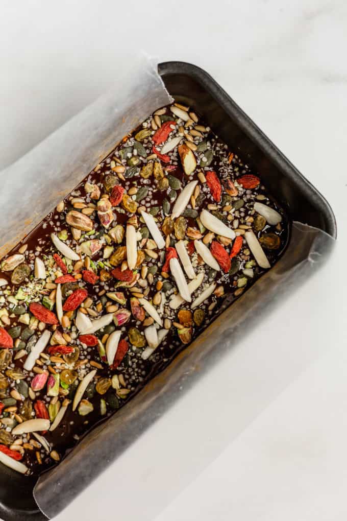a loaf pan with superfood bars in it topped with nuts, seeds and dried fruits