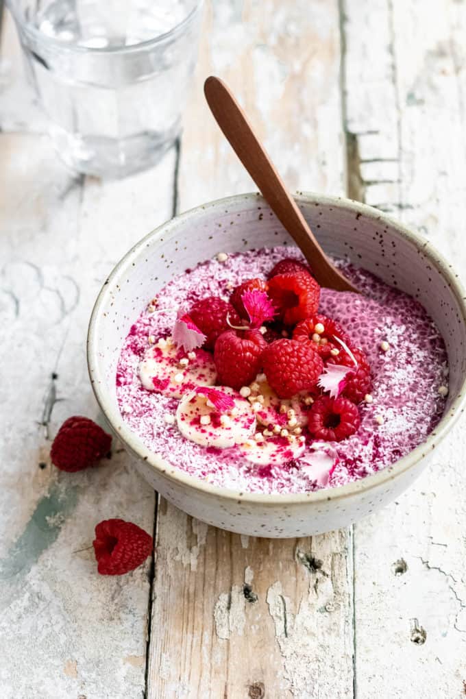 raspberry chia pudding in a bowl topped with raspberries