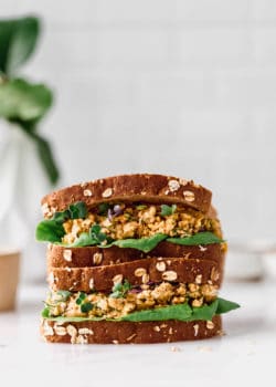 two chickpea salad sandwiches stacked on a marble counter
