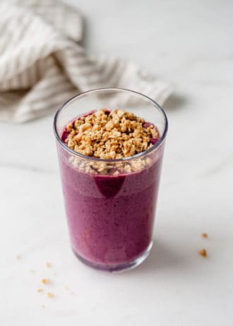 An acai smoothie in a glass topped with granola