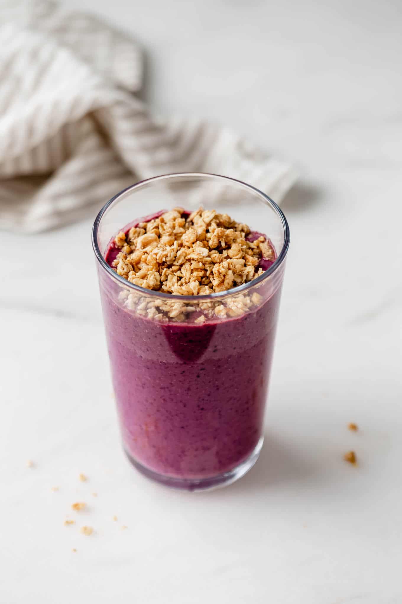 An acai smoothie in a glass topped with granola