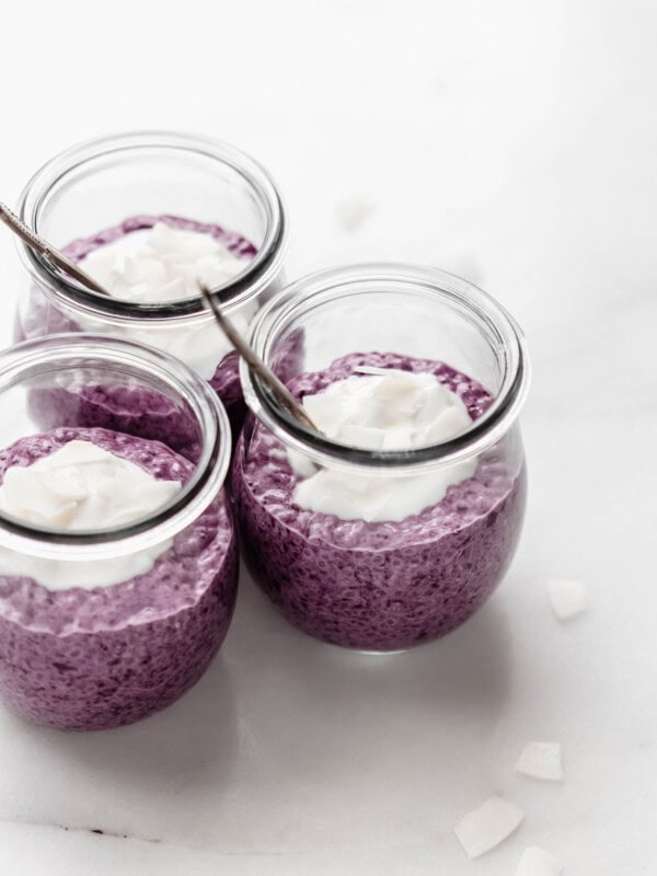 three jars of blueberry chia pudding on a marble counter