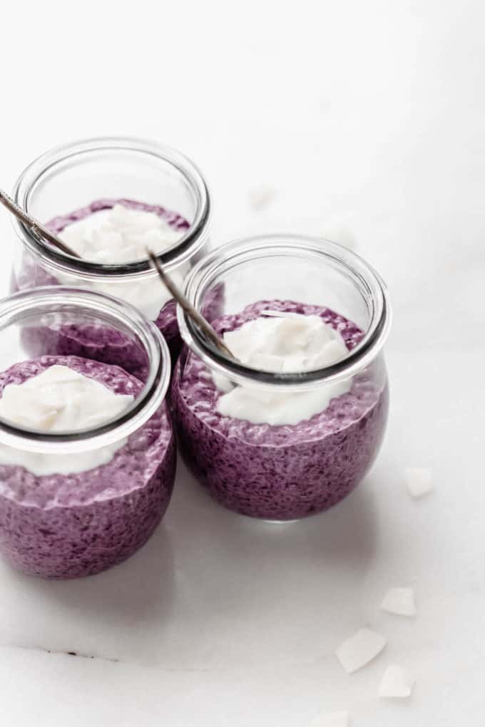 three jars of blueberry chia pudding on a marble counter