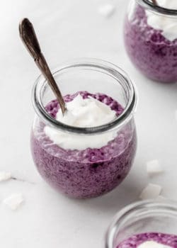 a cup of blueberry chia pudding topped with coconut flakes