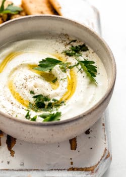 A bowl of whipped feta dip with olive oil and parsley on top