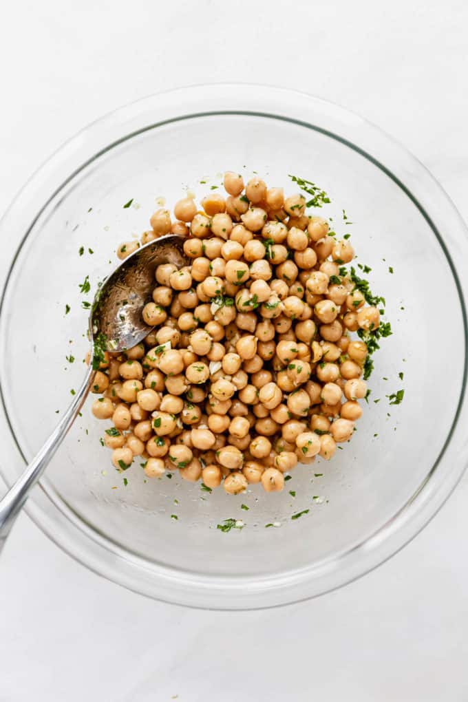 A clear mixing bowl with marinated chickpeas in it