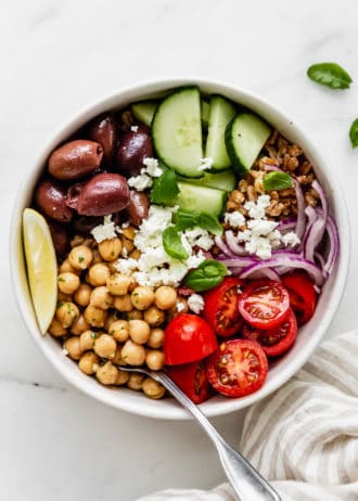 A greek power bowl with chickpeas, cherry tomatoes, olives and cucumber