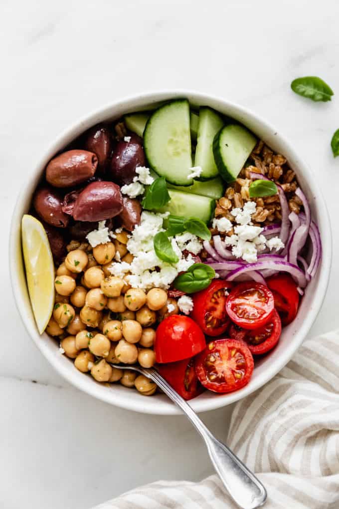 A greek power bowl with chickpeas, cherry tomatoes, olives and cucumber