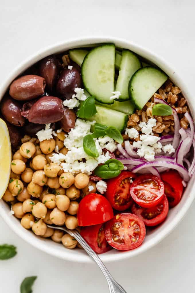 chickpeas, vegetables, and olives in a white bowl