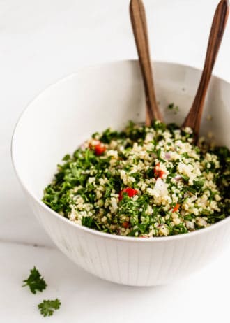 A bowl of quinoa tabbouleh salad with wood serving spoons