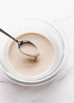 a spoon scooping lemon tahini dressing out of a bowl