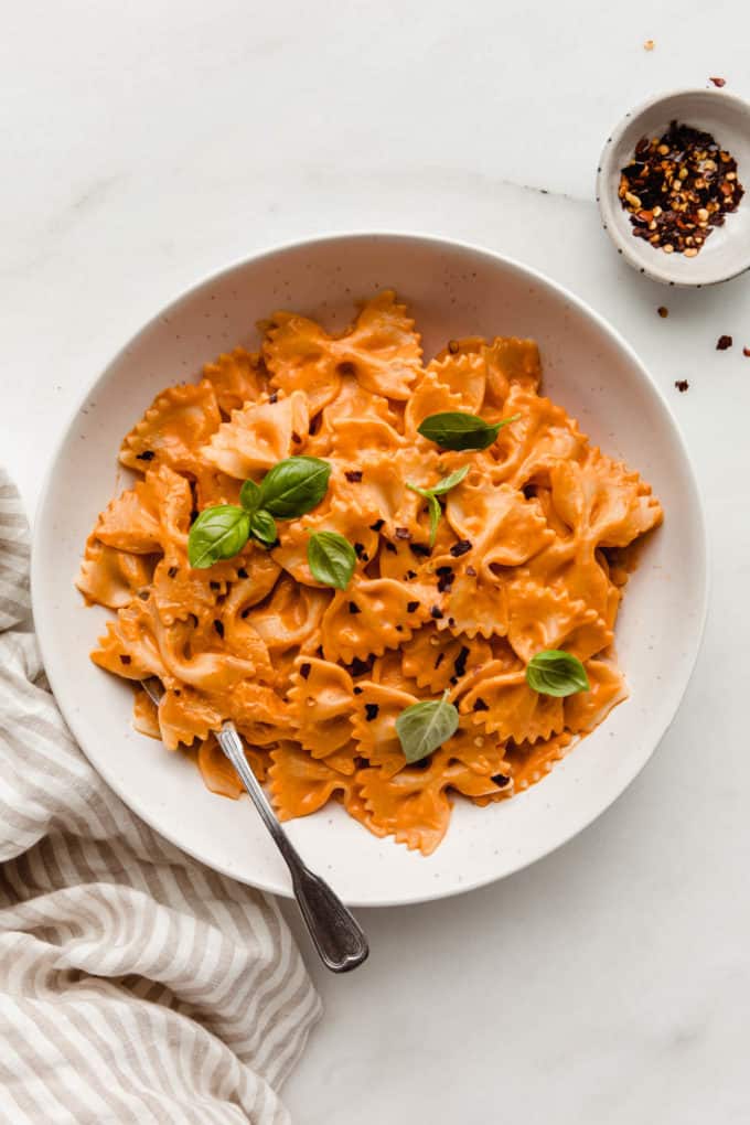 A bowl of vegan vodka pasta topped with basil leaves