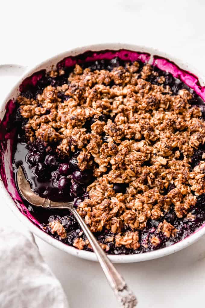A blueberry crisp with a serving spoon