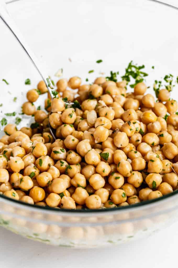 Chickpeas in a mixing bowl with herbs and dressing