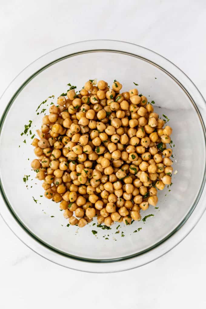 a clear mixing bowl with marinated chickpeas in it