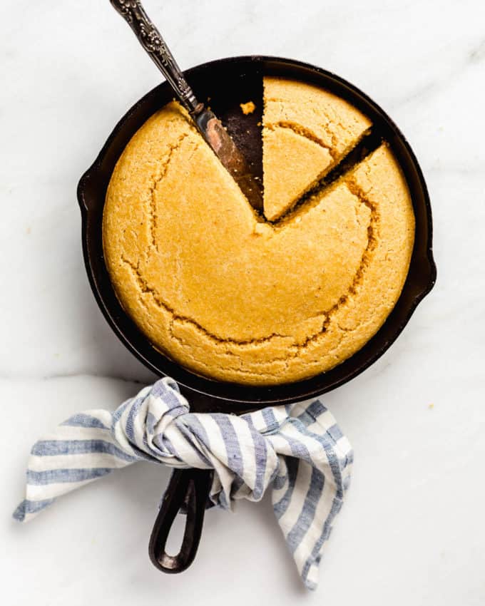 Cornbread in a cast iron skillet with a blue striped napkin tied around the handle