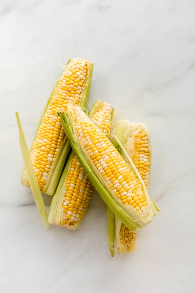 four ears of corn on a marble counter