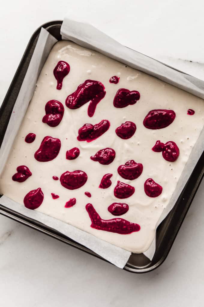 A pan with vegan cheesecake and dollops of raspberry on it
