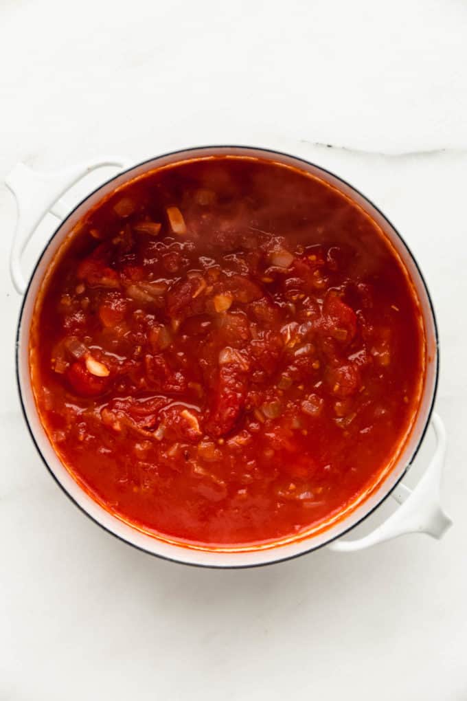 A white pot with tomato sauce in it