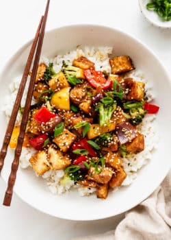 a bowl of tofu stir fry with veggies served over rice