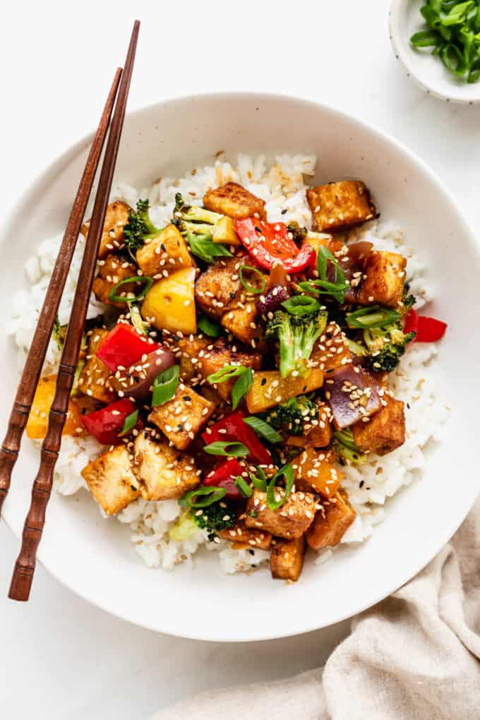 a bowl of tofu stir fry with veggies served over rice