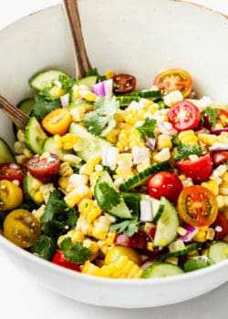 A salad with corn, cucumber and tomato in it