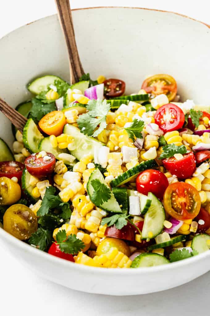 A salad with corn, cucumber and tomato in it