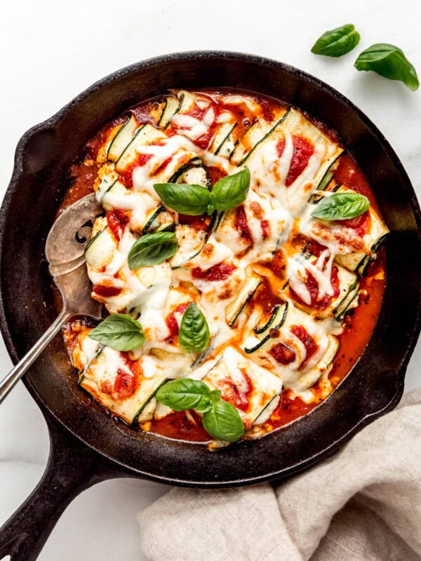 Zucchini involtini in a cast iron skillet topped with fresh herbs