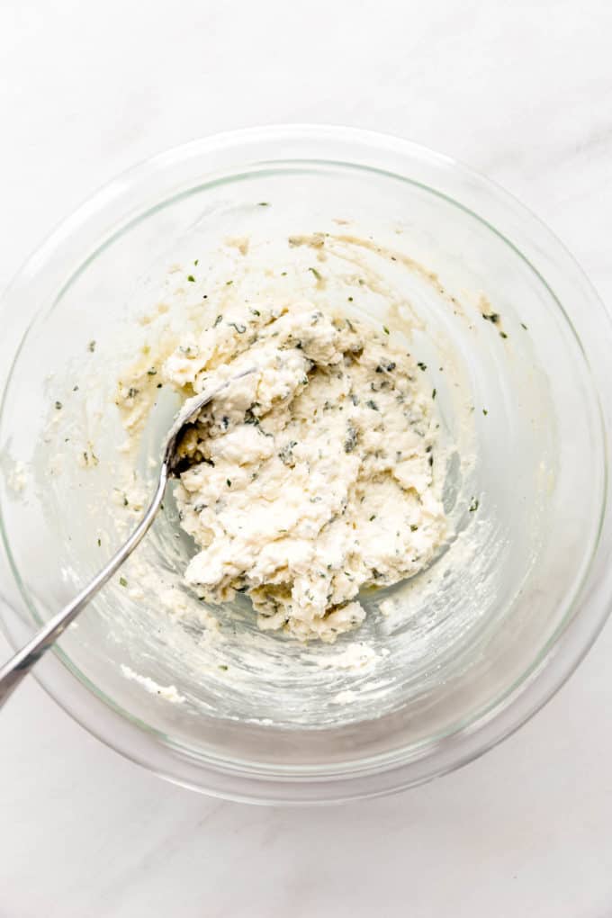 Mixed up ricotta and herbs in a mixing bowl