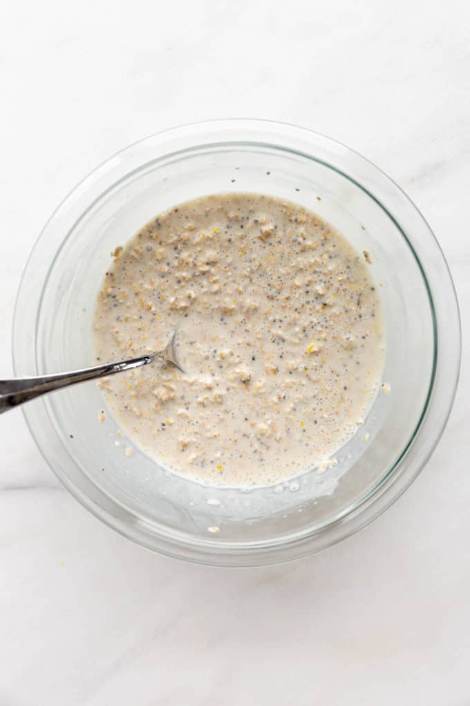 A clear mixing bowl with mixed up oats, chia seeds and oat milk in it