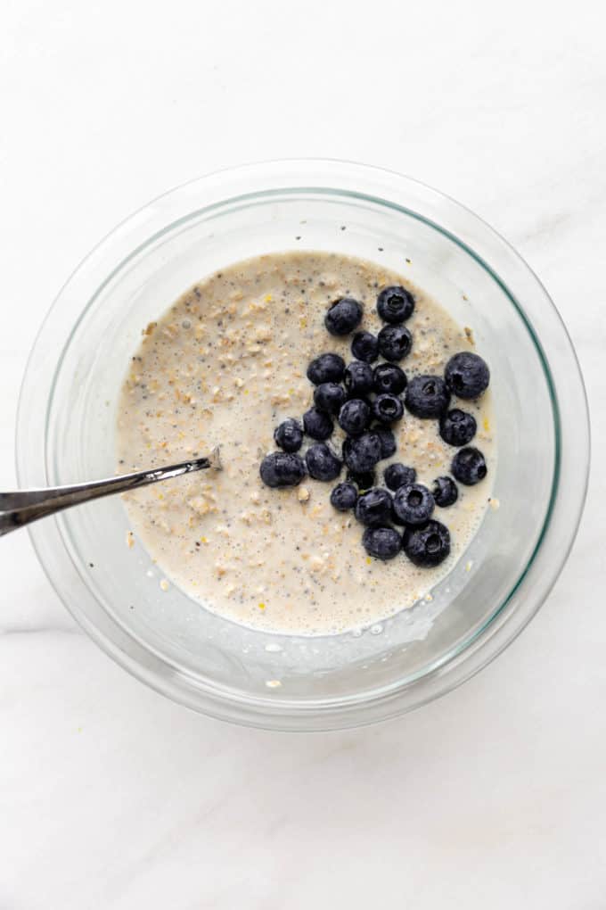 Overnight oats mixture in a mixing bowl with a blueberries