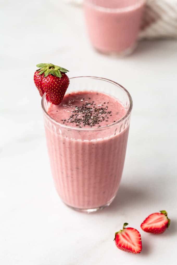 A chia seed smoothie in a glass topped with chia seeds and a strawberry