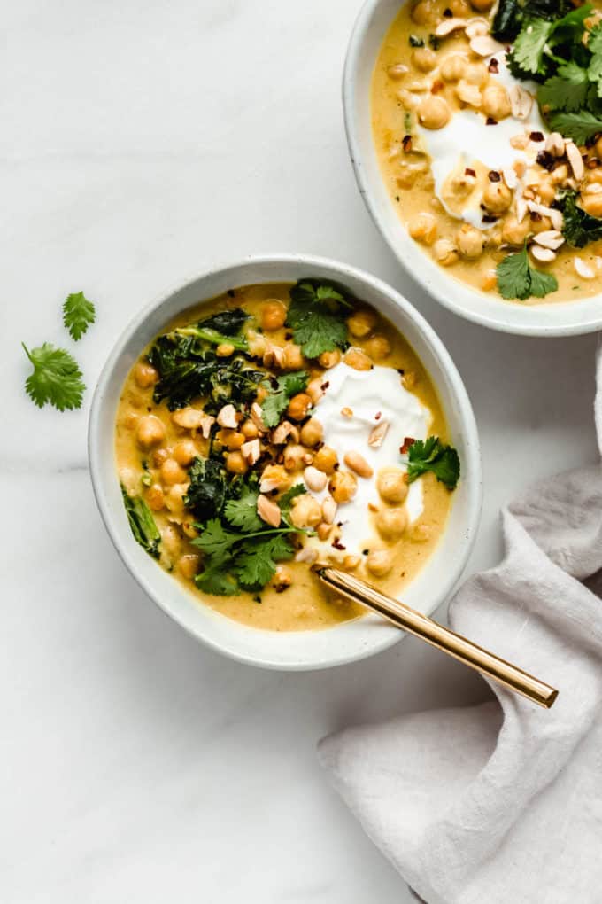 Coconut chickpea curry in a bowl with a gold spoon and a grey napkin on the side