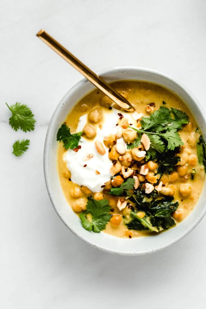 a bowl of coconut chickpea curry topped with yogurt, peanuts and cilantro