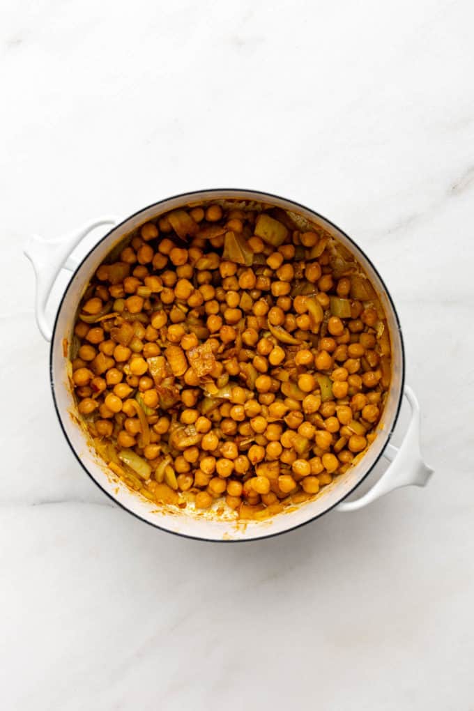 A white pot with chickpeas and curry in it