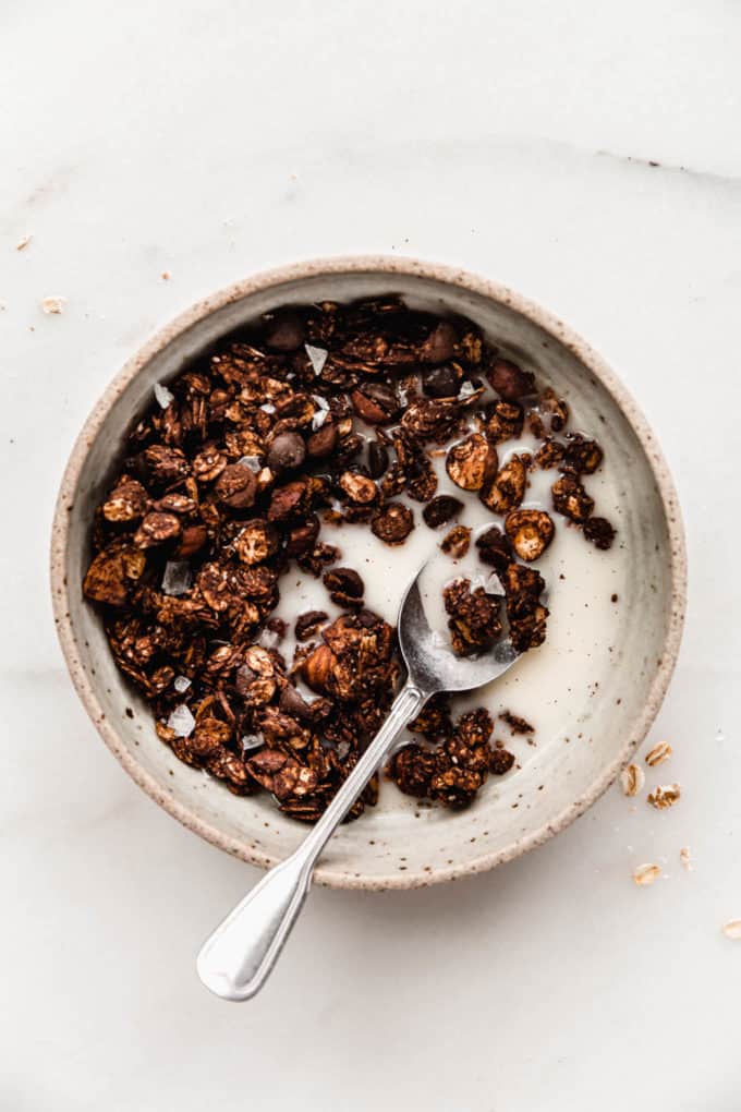 Chocolate granola and almond milk in a speckled white bowl