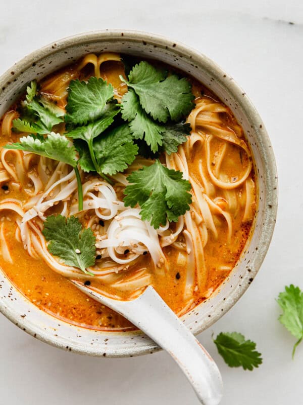A bowl of Thai Coconut Soup with noodles and a soup spoon in it