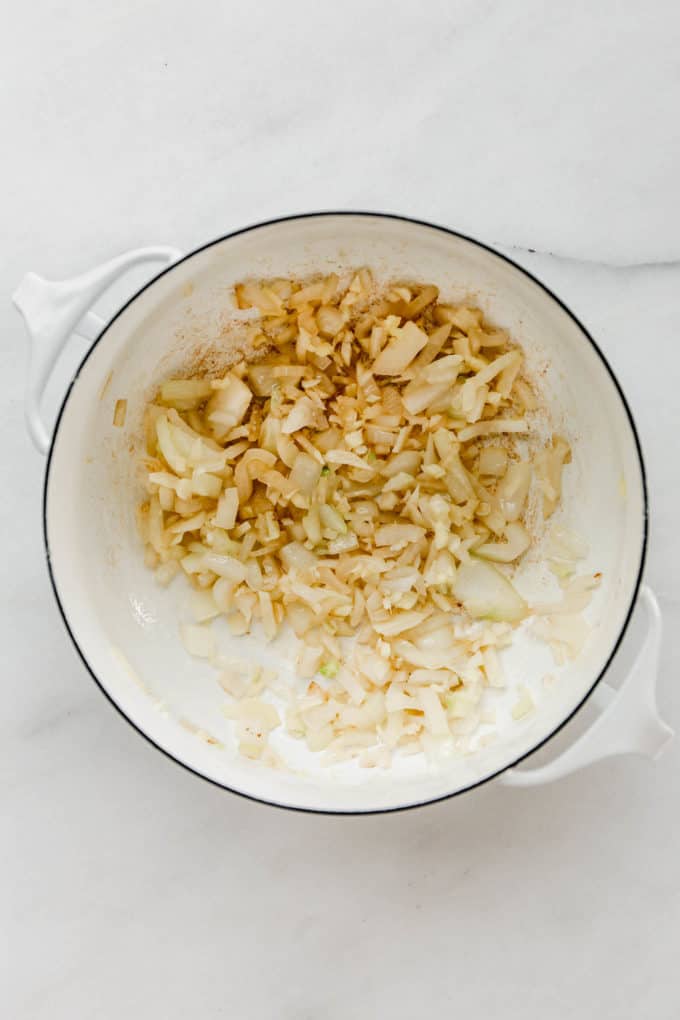 A white pot with chopped onions, garlic and ginger in it