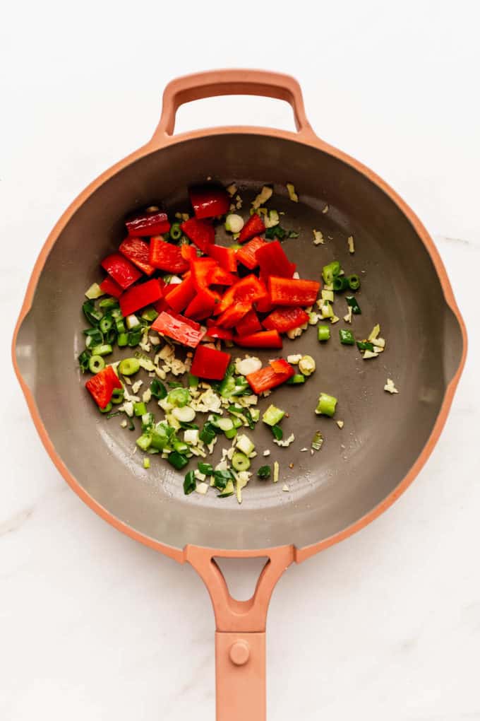 a pan with red pepper and green onions in it