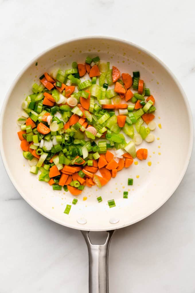 Green onions, celery and carrots in a white pan