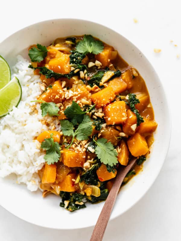 Butternut squash curry in a white bowl with a wood spoon